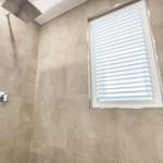 Dusche mit Duschbrause und Fenster mit Jalousie
