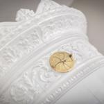 Weißer, verziertes Möbelstück mit goldenem Knopf.