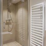 Dusche mit Glaswand und Heizkörper an der Wand