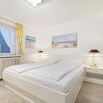 Bedroom with white bed, window, and wall pictures