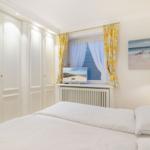 Bedroom with bed, wardrobe, and window with yellow curtains.