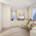 Room with white cabinets, windows with yellow curtains, and a TV.