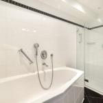 Bath with bathtub and shower, white tiles, black floor tiles