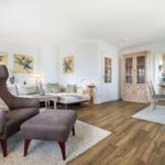 Living and dining area with seating, hardwood floor, and glass-front cabinet.