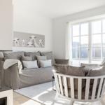 Living room with fireplace, sofa, and round chair. Window with view of outdoor area.