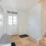 Entrance with wooden stairs, white doors, and stone floor