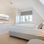 Bedroom with bed, window, and TV mounted on the wall.