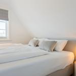 Bedroom with bed, window, and nightstand with lamp.
