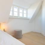 Bedroom with sloped ceiling, windows, and bed.