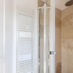 Shower enclosure with glass door and heater on the wall