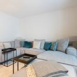 A living room with a large gray sectional sofa and two black tables.