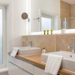 Bathroom with two sinks, wooden countertop, and floor-to-ceiling mirror