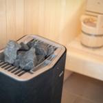 Sauna with stone heater and wooden bench in background