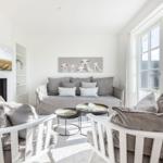 Living room with fireplace, sofa, and two chairs. Pictures hang on the walls.
