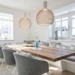 Dining room with wooden table, bench, and two pendant lamps.