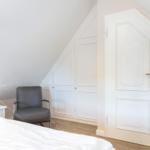 Bedroom with bed, chair, and nightstand under sloped ceiling