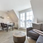 Living and dining area with sofa, table, and windows to the terrace.