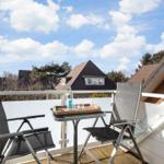 Terrace with two chairs and table. Background: houses and blue sky.
