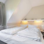 Room with double bed, window, and floating desk under sloped ceiling.