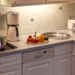 Kitchen with sink, stove, coffee maker, and fruit on countertop.