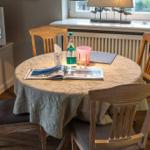 Round table with four chairs, tablecloth, magazines, and drinks.
