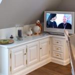 TV on white cabinet with decorative figures and candle