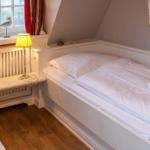 Bedroom with white bed, nightstand, and window with seagull figurines.