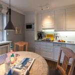 Kitchen with dining area, white cabinets, and wooden chairs. Window with view outside.