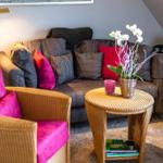 Living room with sofa, chairs, and table. Decorated with flowers and cushions.