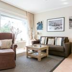 Living room with brown sofa, armchair, and glass coffee table. Large sliding door to garden.