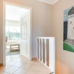 Hallway with staircase railing and lighthouse painting on the wall.