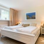 Bedroom with white bed, window, and picture on the wall.