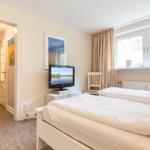 Bedroom with bed, TV, and window with curtains.