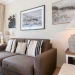 A living room with a brown sofa, cushions, and wall art.