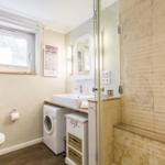 Bathroom with shower, washing machine, and window