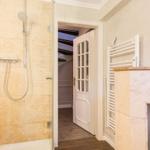 Shower with glass enclosure, door to hallway, and heater