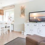 Living and dining area with TV, dining table, and beach decor.
