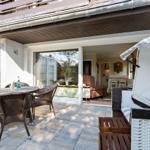 Terrace with table and chairs, view into house with seating area.