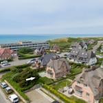 Haus mit Dach und Garten, Blick auf Meer und Strand.
