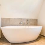 Freistehende Badewanne in Dachschrägen-Badezimmer mit Steinwand und Fenster
