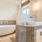 Bad mit freistehender Badewanne und Waschbecken auf Marmorunterbau.