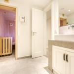Badezimmer mit Dusche, Waschtisch und Sauna im Hintergrund.