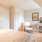 Schlafzimmer mit Bett, Schreibtisch, Fernseher und Kleiderschrank.