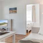 Wohnzimmer mit Sofa, Fernseher und Blick in Schlafzimmer