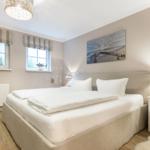 Bedroom with double bed, two windows, and wall art.