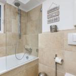 Bathroom with bathtub, shower, and window.