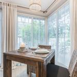 Dining room with wooden table, chairs, and windows to the garden.