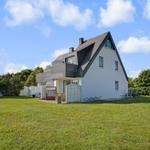 Weiße Villa mit grünem Garten und Fahrrädern