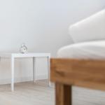 Ein weißer Tisch mit Wecker neben einem Sofa