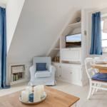 Wohn- und Essbereich mit TV, Bücherregal und Terrassentür.